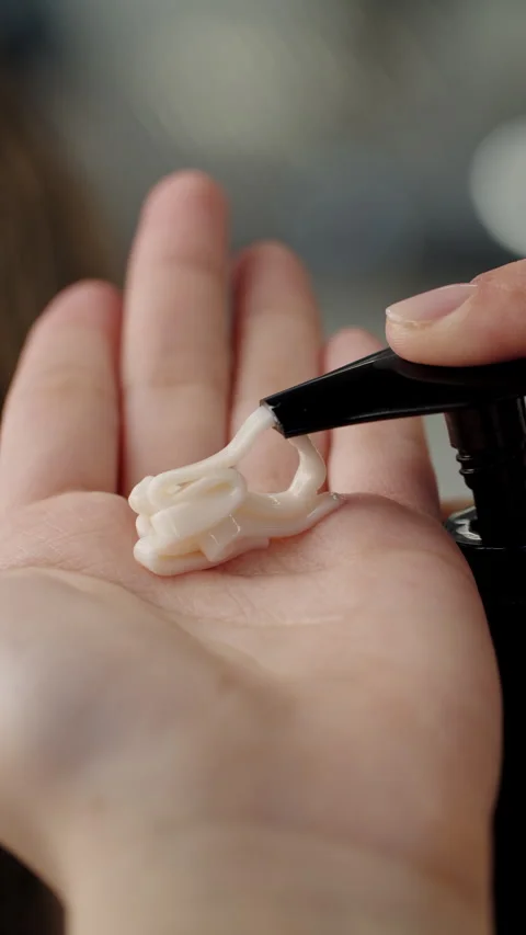 Hands pushing pump plastic lotion bottle applying moisturizing cream on hands Video stock 311162965