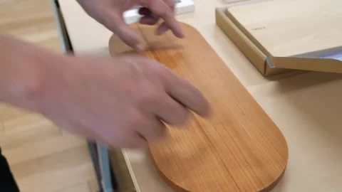 Hands Pushing a Rounded Wooden Chopping Board Across a Table Stock Footage 340900653