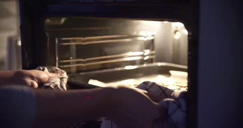 Hands put a baking sheet with cookies in electric oven, close up. Home baking Vidéo 247496070