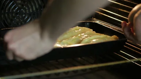 Hands put a baking sheet of pies in the oven and close the door Video stock 149982043