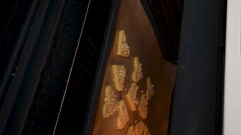 Hands put a baking tray with heart shaped cookies on the sheet in electric oven  Stock Footage 263244736