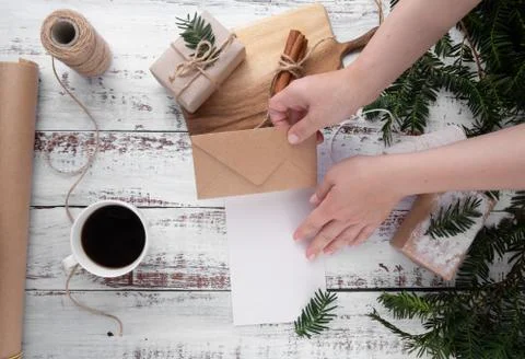 Hands put craft envelope on postcard. near handmade gifts, Foto stock