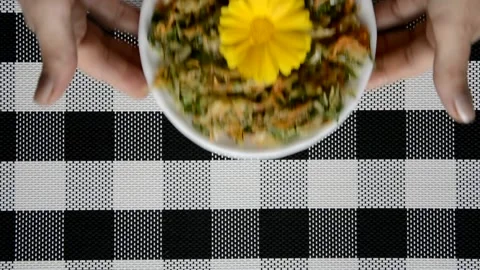 Hands put a Cup of salad, decorated with a marigold flower, on the table. Rea Stock Footage 136539335