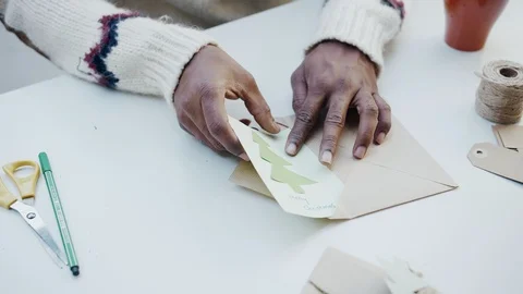 Hands put into envelope green Christmas tree postcard and writing happy message Video stock 101040787