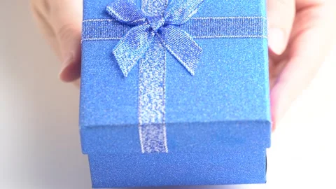 Hands put a gift box on the table, presented with a gift. Glittering blue g.. Stock Footage 254887457