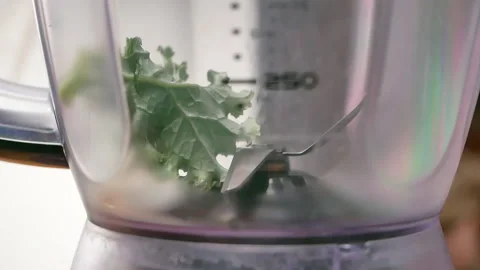 Hands put green leaf salad Kale in blender to prepare detox green smoothie. 動画素材 157408813