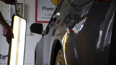 Hands put LED lamp next to the car and illuminate the dent from the impact Stock Footage 113109572