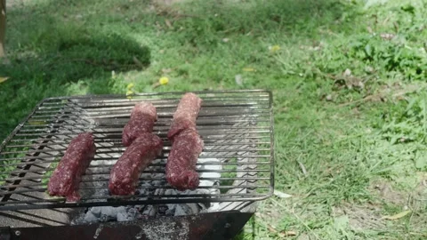 Hands put meat sausages on the grill in nature, in a clearing 库存影片 217518523