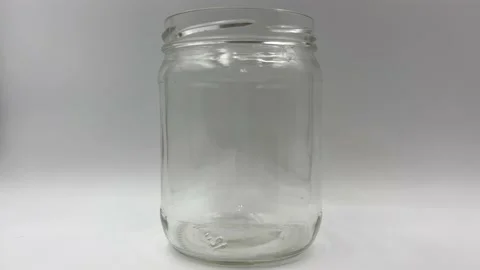 Hands put money into a tip jar or home savings, filling up the jar with dollars Stock Footage 170307349
