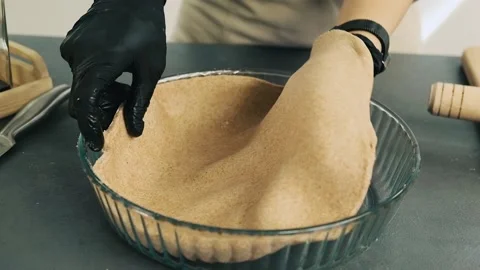 Hands put rolled dough into baking form to cook delicious pastry. Preparing and Stock Footage 136182229