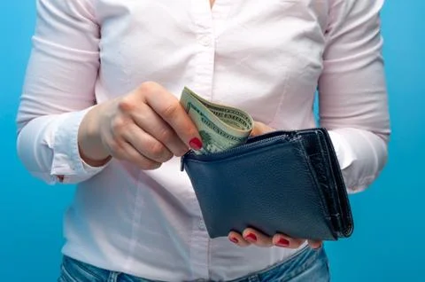 Hands put rolled paper banknotes in a purse Foto stock