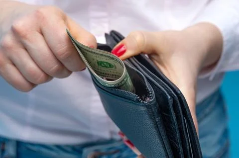 Hands put rolled paper banknotes in a purse 스톡 사진