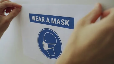 Hands put up a sign requires face mask then take it down or remove it from wall Stock Footage 158505514