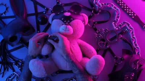 Hands put on a toy bear leather handcuffs on the table with a BDSM accessory Stock Footage 144666450