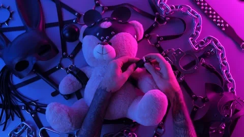 Hands put on a toy bear leather handcuffs on the table with a BDSM accessory Stock Footage 144666527