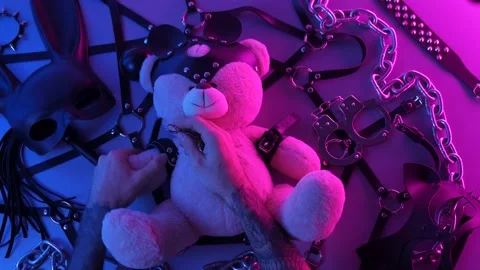 Hands put on a toy bear leather handcuffs on the table with a BDSM accessory Stock Footage 144666638