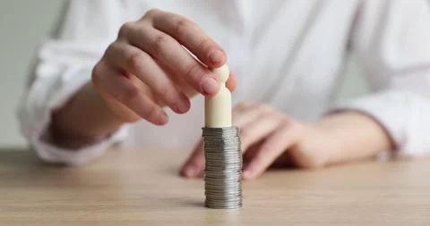 Hands put a wooden doll on the stack of coins Stock Footage 258906046