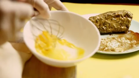 Hands puts bowl with beaten egg close to formed raw beef Wellington. 4k video Stock Footage 156301986