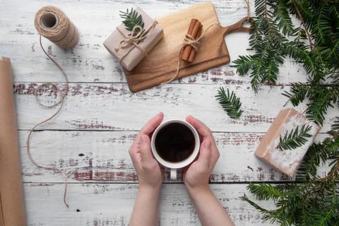 Hands puts cup of coffee on the table with gifts Foto stock