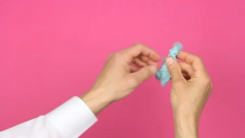 Hands puts on right hand blue medical glove, first person view, pink background Video stock 126998876