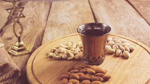 Hands puts the table on a round stand with nuts and sets the kiddush wine Stock Footage 150648317