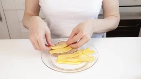 Hands putting cheese on bread on kitchen table, young person slicing cheese.. Stock Footage 297247338