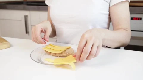 Hands putting cheese on bread on kitchen table, woman preparing a sandwich .. Stock Footage 303216917