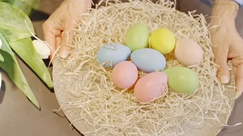 Hands putting colorful Easter Eggs on the Table close to spring flowers Stock Footage 236341737