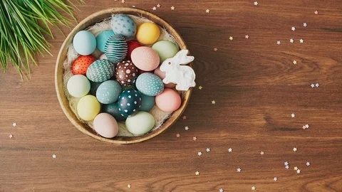 Hands putting down nest full of colorful Easter eggs and tulips on decorated  Stock Footage 124383439