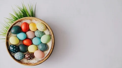 Hands putting down tulips next to Colorful Easter eggs in basket on bright ba Stock Footage 124382740