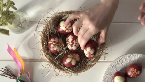 Hands putting homemade Easter eggs dyed with onion peels into a wicker basket Video stock 171942659