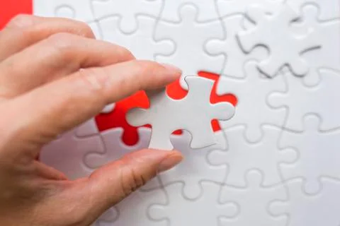 Hands putting the last missing piece of the puzzle. Stock Photos
