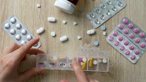 Hands putting pills into pill box, top view Stock Footage 260821083