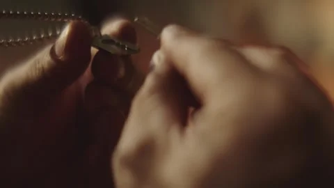 Hands putting small silver metal key pendant onto neck chain necklace for j.. Stock Footage 337601755