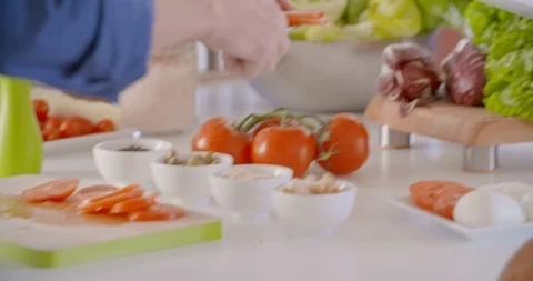 Hands putting tomatoes on dish. Young people couple cooking and preparing food Видео 108101087