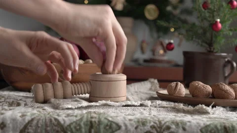 Hands putting a walnut into a nutcracker, with a decorated Christmas tree Stock Footage 170849697