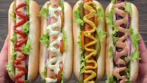 Hands raise four deliciously prepared hot dogs and various sausages Stock Footage 302849045