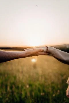 Hands reaching out during sunset in a peaceful field Stock Photos