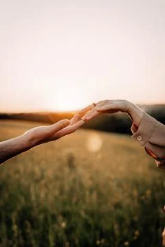 Hands reaching out during sunset in a peaceful field Stock Photos