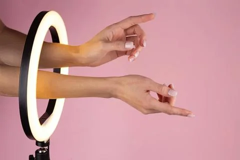 Hands reaching out through a circular light ring on pink background Stock Photos