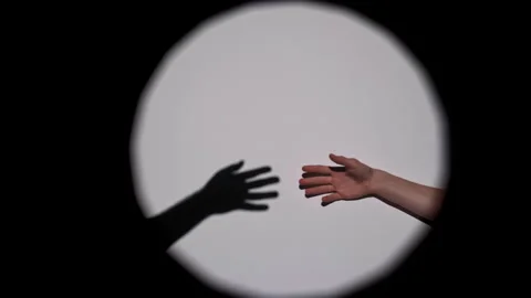 Hands Reaching Towards Shadow in Spotlight Illumination Stockbeeldmateriaal 311932988
