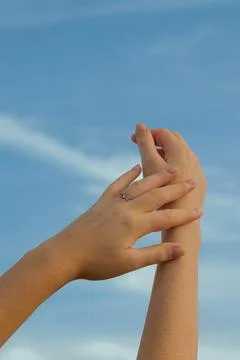 Hands reaching towards sky during sunny day with clouds above in an outdoor.  库存照片