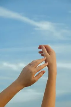 Hands reaching towards sky during sunny day with clouds above in an outdoor.  库存照片