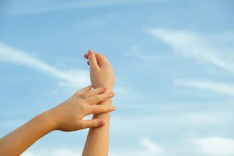 Hands reaching towards sky during sunny day with clouds above in an outdoor.  库存照片