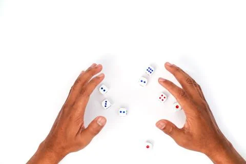 Hands Reaching For White Dice With Red and Blue Dots On White Background Stock Photos