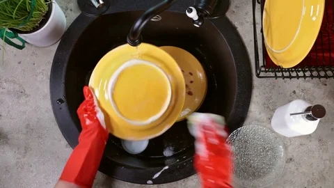 Hands in red rubber gloves washing a yellow plate Stock Footage 80241798