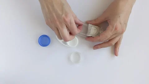 Hands remove a contact lens from open plastic blister pack Stock Footage 330552337