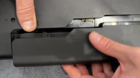 Hands removing battery from laptop underside compartment, portable computer Stock Footage 337121463