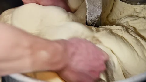 Hands removing dough from mixer, showing texture and consistency in kitchen Stock Footage 335191393