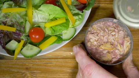 Hands removing the lid from a tin of chopped tuna, next to a plate of salad. Stock Footage 144928306